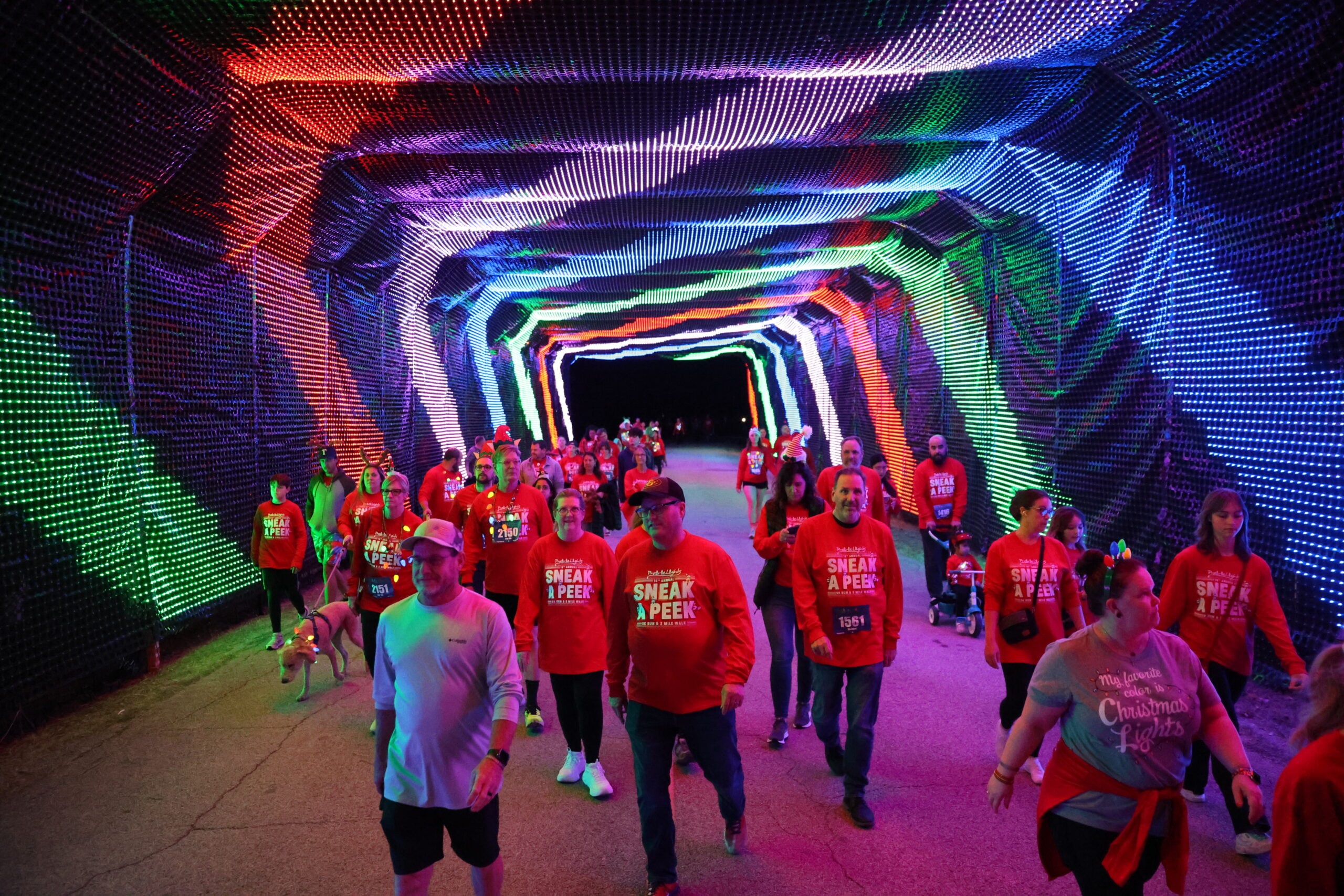 Runners passing under an illuminated tunnel of holiday lights at Prairie Lights